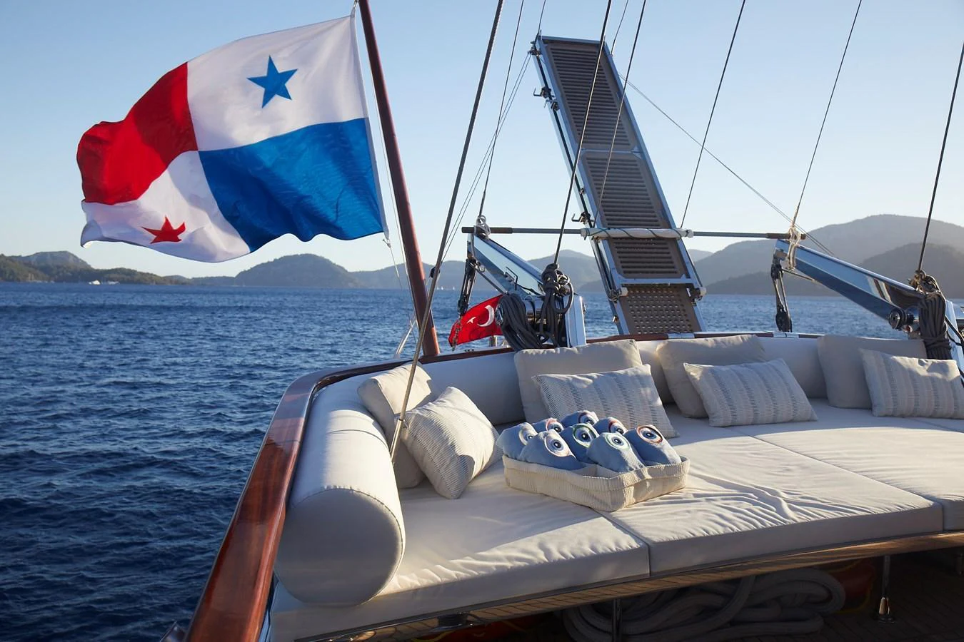 A luxurious lounging area on the deck of a yacht, adorned with plush cushions and a flag waving in the breeze. aboard WHITE WINGS Yacht for Sale