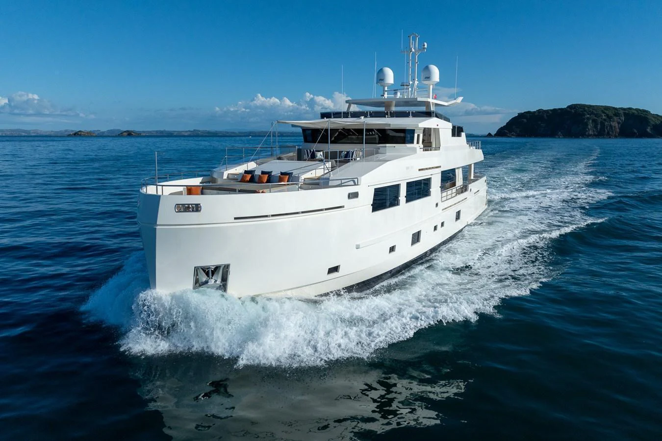A sleek white yacht cruises through calm blue waters, showcasing its modern design and spacious deck. aboard NYLA Yacht for Sale