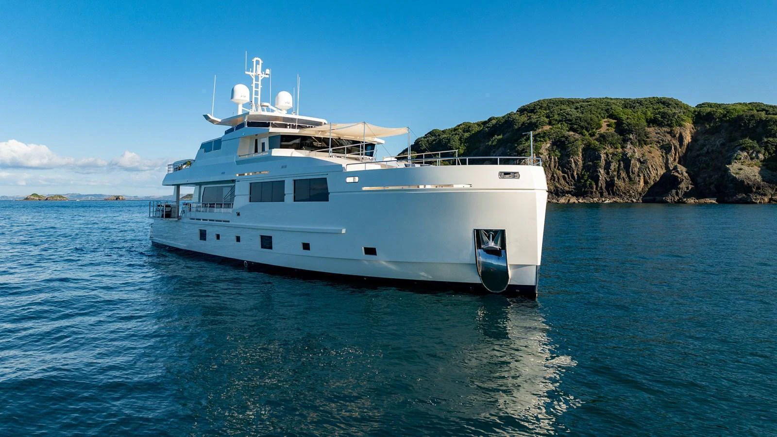 A sleek and modern yacht glides gracefully on calm waters with a scenic coastal backdrop. aboard NYLA Yacht for Sale