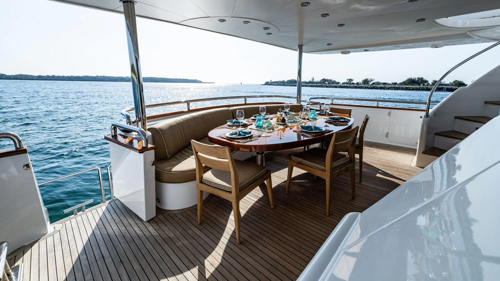 The aft deck features an elegant dining area with a stunning view of the water. aboard THE CLUBHOUSE Yacht for Sale