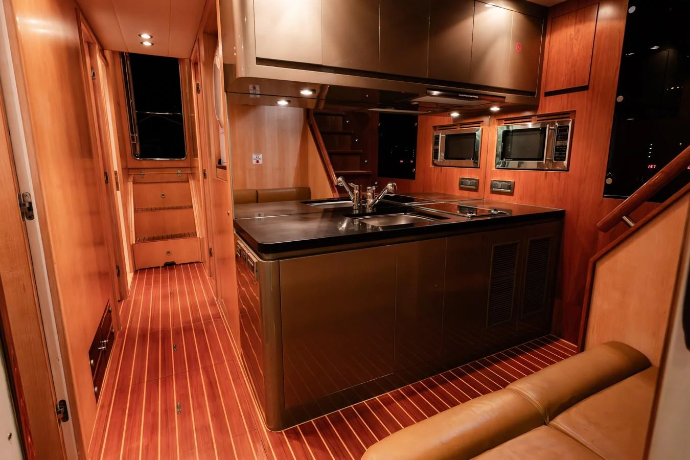 The yacht's galley features modern appliances and elegant wood finishes, creating a warm and inviting atmosphere. aboard THE CLUBHOUSE Yacht for Sale