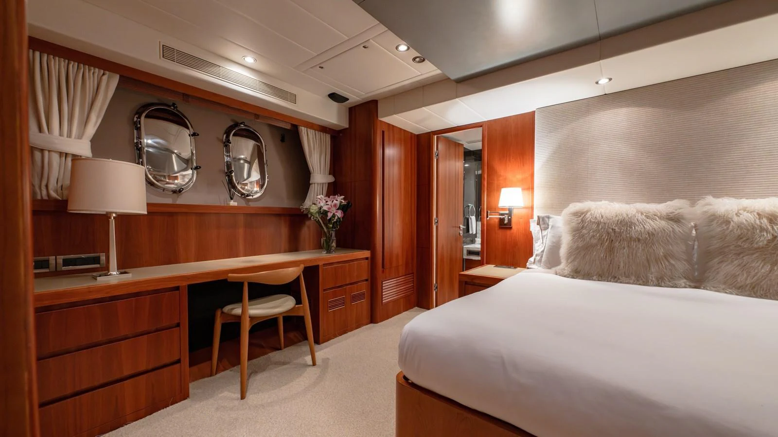 A luxurious stateroom featuring elegant wood finishes and plush bedding. aboard THE CLUBHOUSE Yacht for Sale
