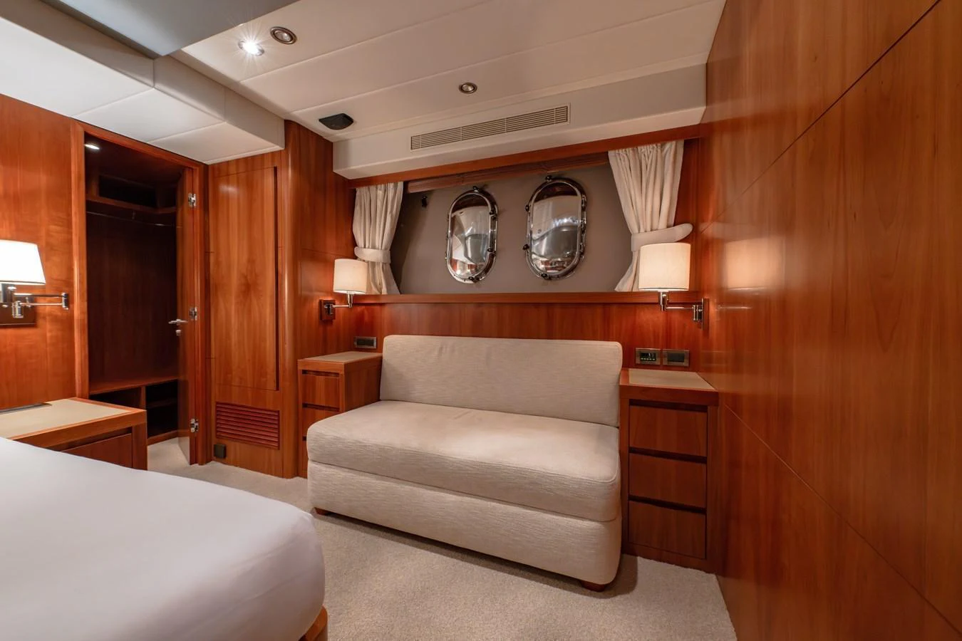 A cozy stateroom with warm wooden paneling and a comfortable seating area. aboard THE CLUBHOUSE Yacht for Sale
