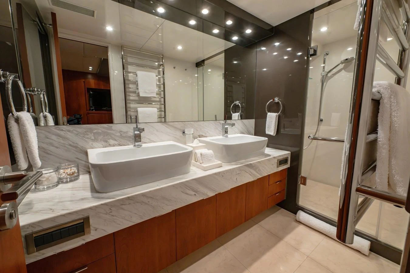 The yacht's bathroom features a luxurious double sink vanity with modern fixtures and ample lighting. aboard THE CLUBHOUSE Yacht for Sale