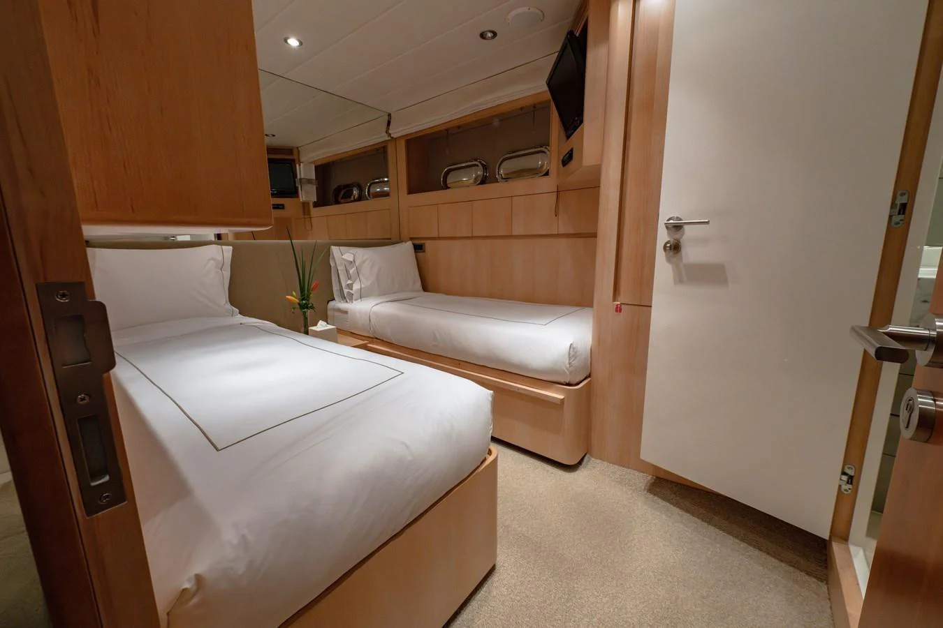 The guest cabin features two single beds with modern wooden finishes and a cozy ambiance. aboard THE CLUBHOUSE Yacht for Sale