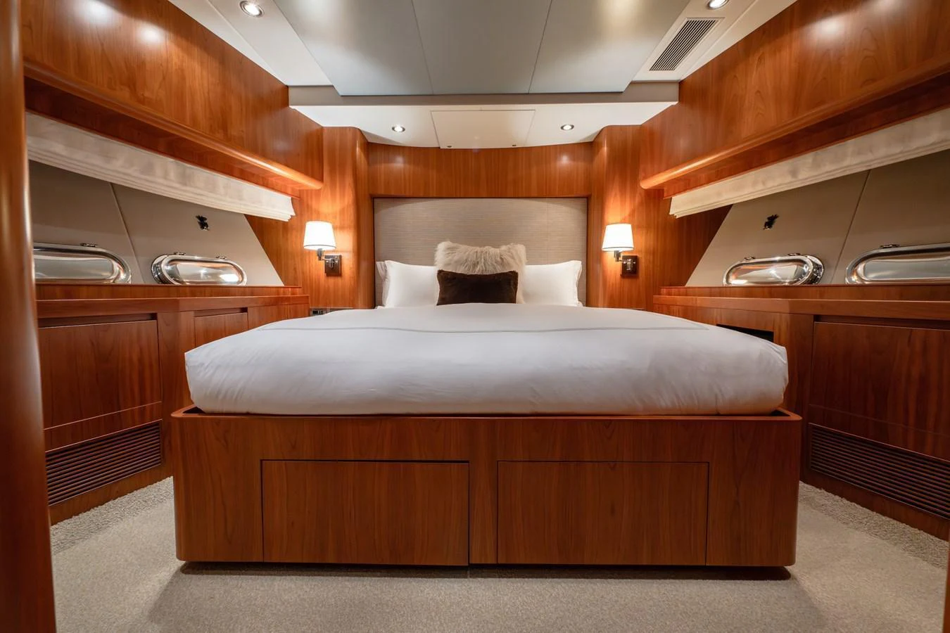 The stateroom features a luxurious bed with elegant wood paneling and ambient lighting. aboard THE CLUBHOUSE Yacht for Sale