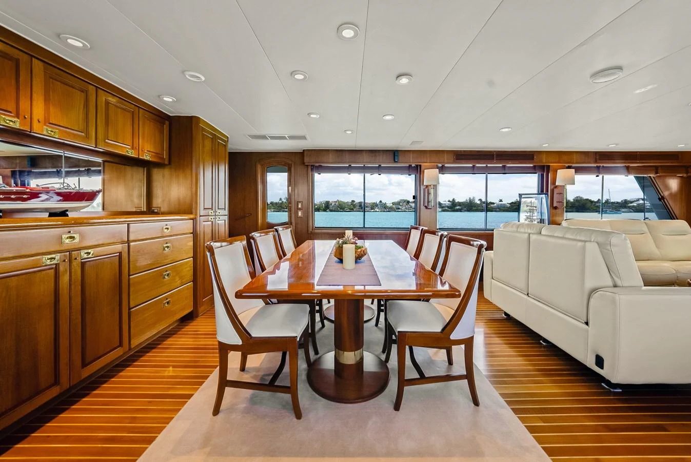 The yacht's dining area features elegant wooden cabinetry and a large table with comfortable seating, offering stunning views through expansive windows. aboard SERENITY Yacht for Sale