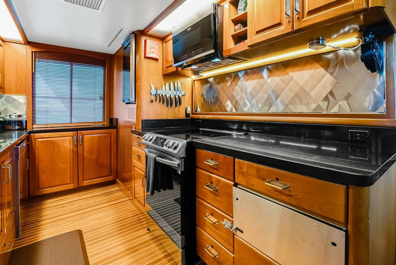 The yacht's galley features modern appliances and ample wooden cabinetry, creating a warm and functional cooking space. aboard SERENITY Yacht for Sale