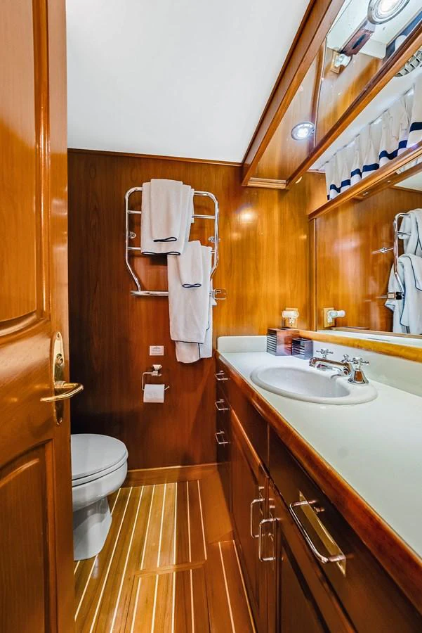 The yacht's bathroom features elegant wooden cabinetry and modern fixtures. aboard SERENITY Yacht for Sale