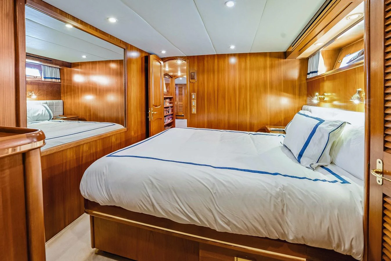 A cozy stateroom featuring a comfortable bed with elegant bedding and warm wooden paneling. aboard SERENITY Yacht for Sale