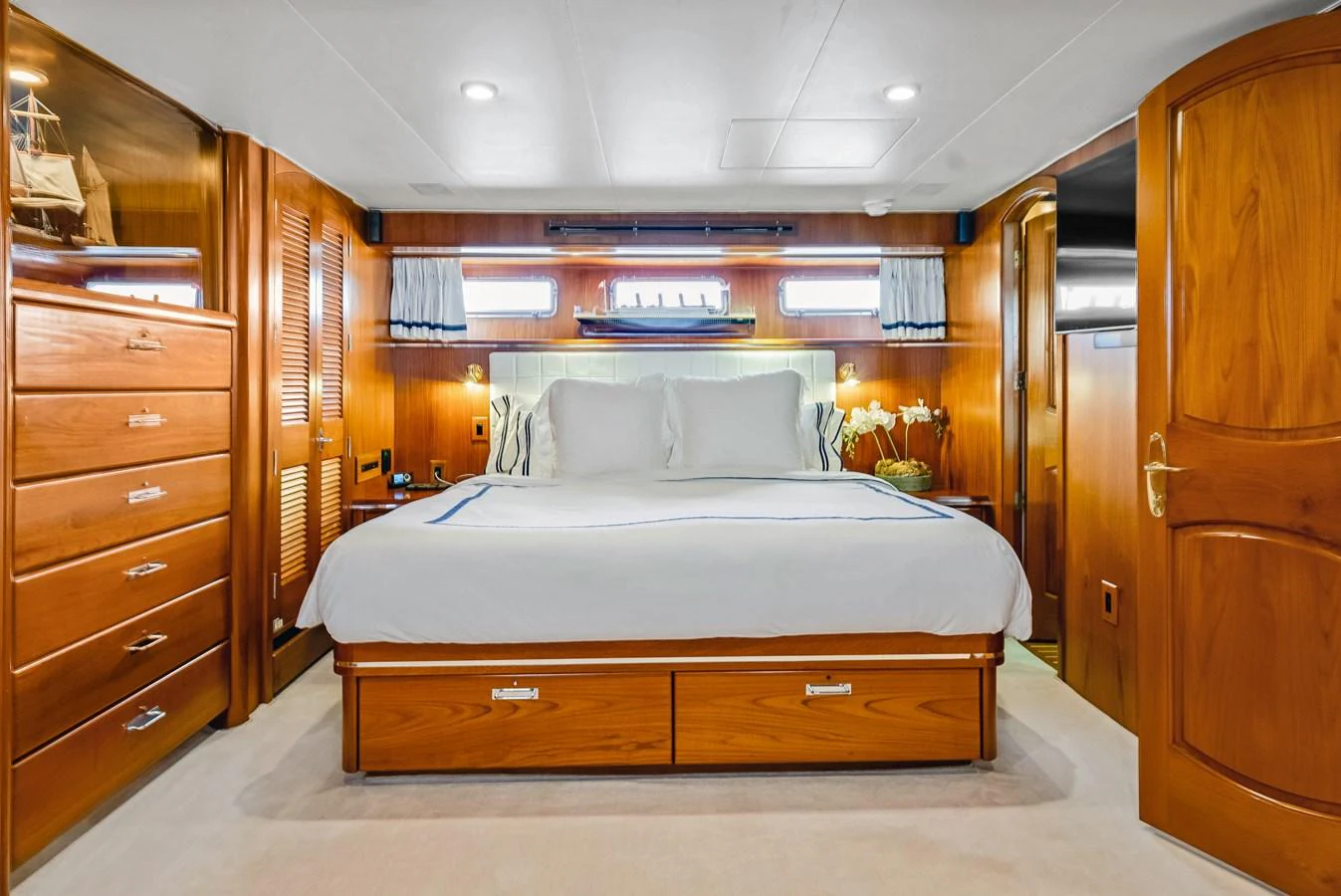 The master stateroom features a luxurious bed with elegant wooden furnishings and ample natural light. aboard SERENITY Yacht for Sale