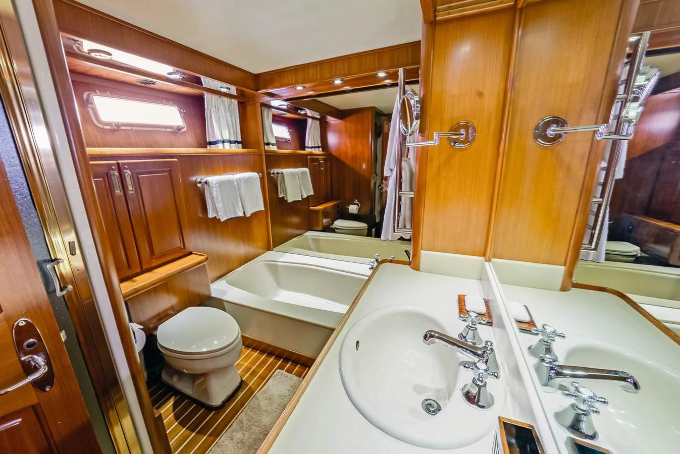 The yacht's bathroom features elegant wood paneling, a spacious sink area, and a comfortable bathtub. aboard SERENITY Yacht for Sale