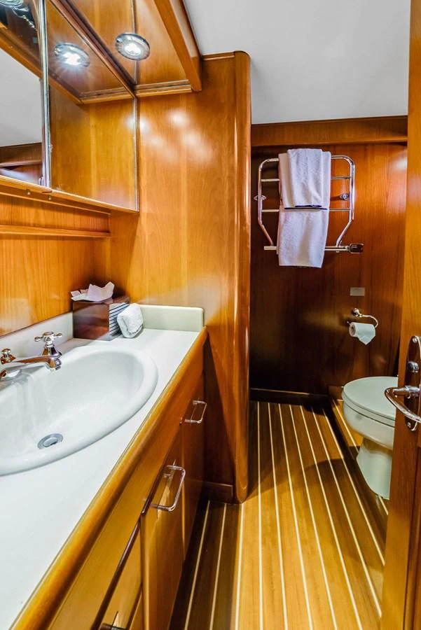 A well-appointed yacht bathroom featuring wooden cabinetry and modern fixtures. aboard SERENITY Yacht for Sale
