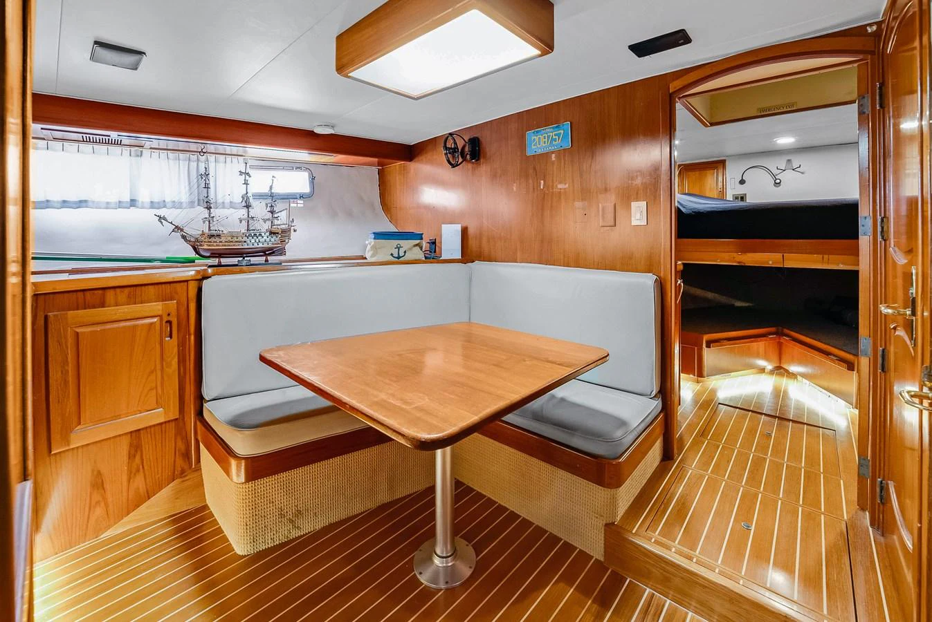 The yacht's dining area features a cozy booth with wooden accents and a model ship display. aboard SERENITY Yacht for Sale