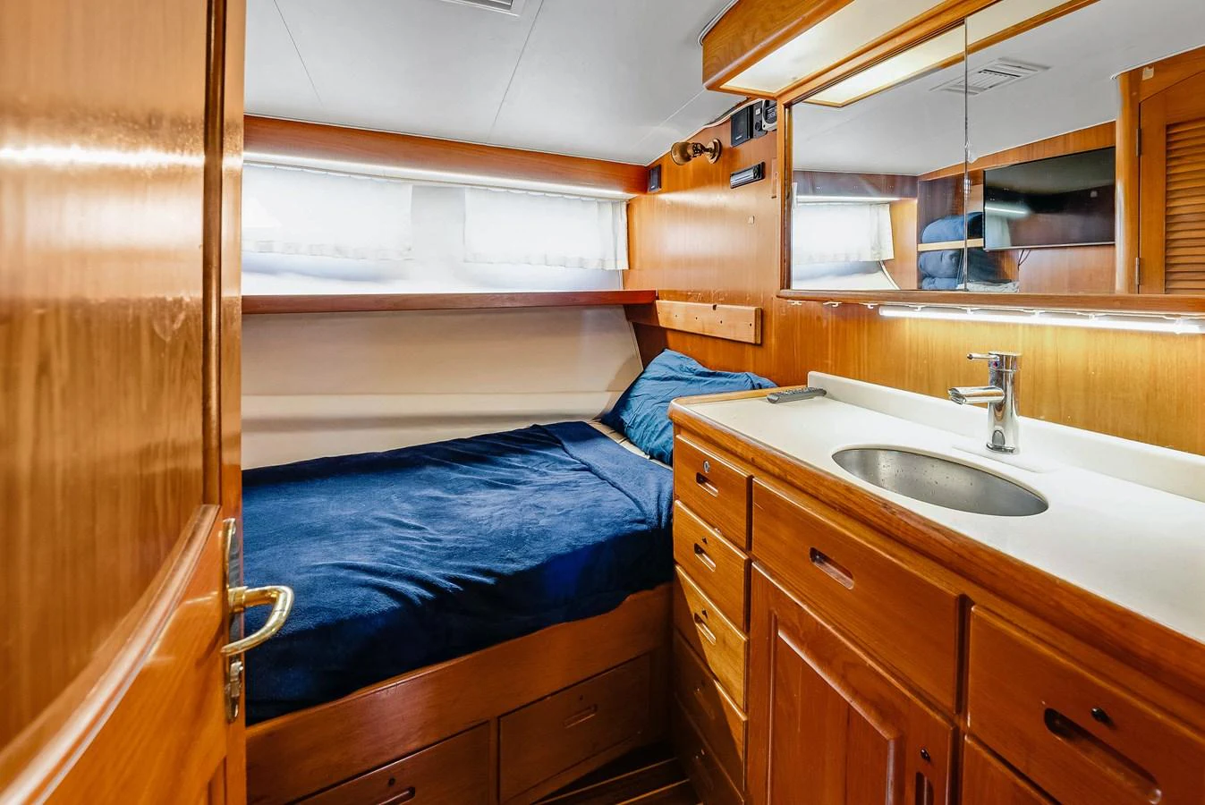 The cozy cabin features a comfortable bed and ample storage space with a sleek wooden finish. aboard SERENITY Yacht for Sale