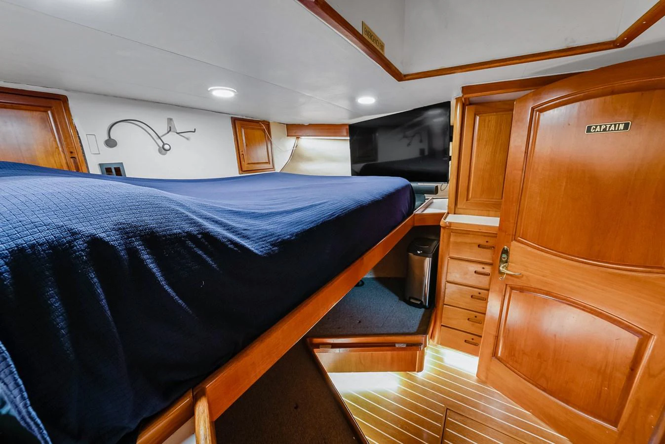 The captain's cabin features a comfortable bed and ample storage space in a warm, wood-paneled setting. aboard SERENITY Yacht for Sale
