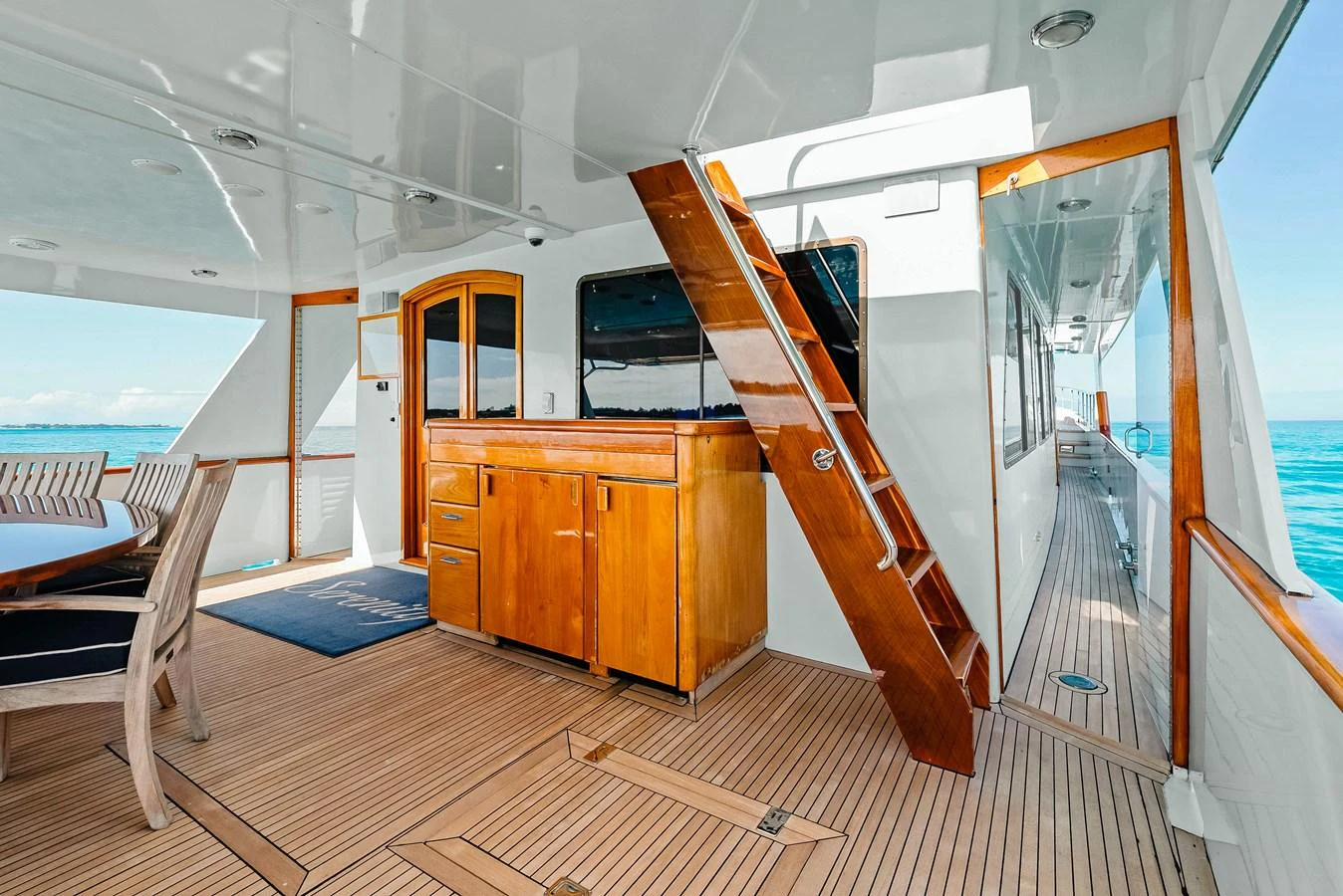 The aft deck features a spacious seating area with wooden cabinetry and access to the side deck. aboard SERENITY Yacht for Sale