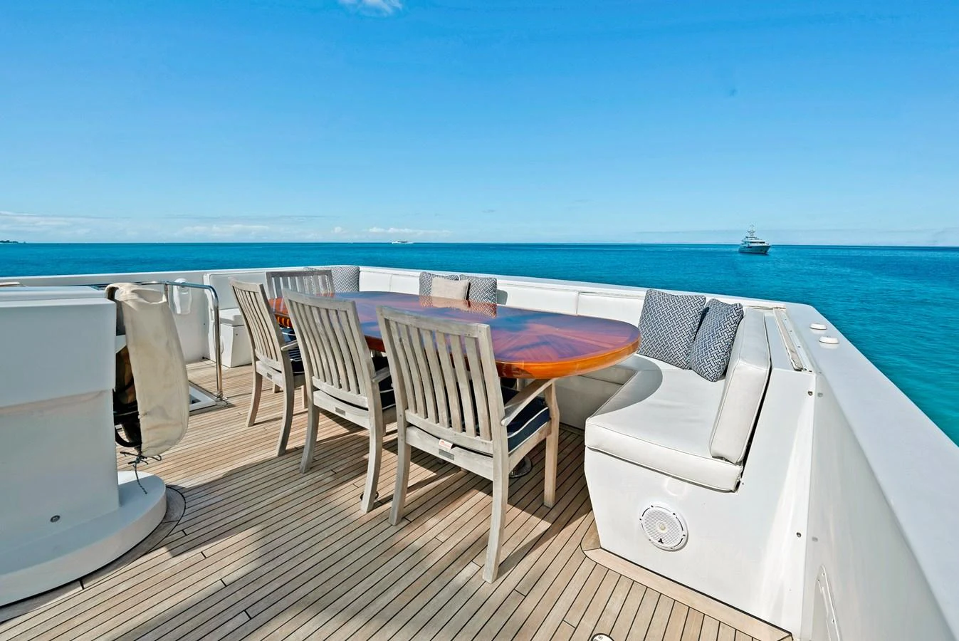 The aft deck features a stylish dining area with a wooden table and cushioned seating, perfect for alfresco meals with a stunning ocean view. aboard SERENITY Yacht for Sale