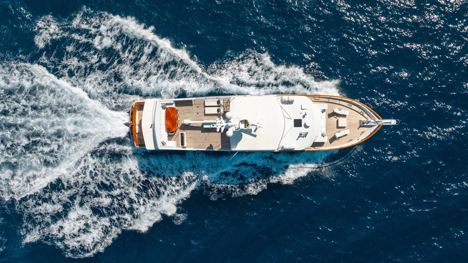 A stunning aerial view of a yacht cruising through the open sea, showcasing its sleek design and spacious deck. aboard SERENITY Yacht for Sale