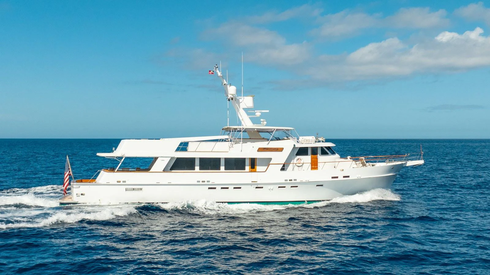 A classic white yacht cruises smoothly on the open sea under a clear blue sky. aboard SERENITY Yacht for Sale