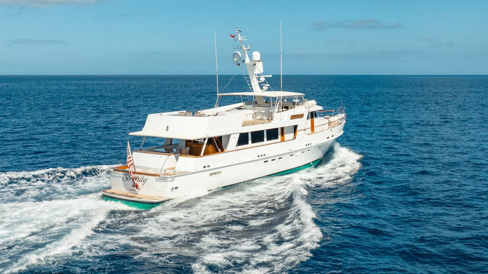A classic yacht cruises gracefully on the open sea under a clear blue sky. aboard SERENITY Yacht for Sale