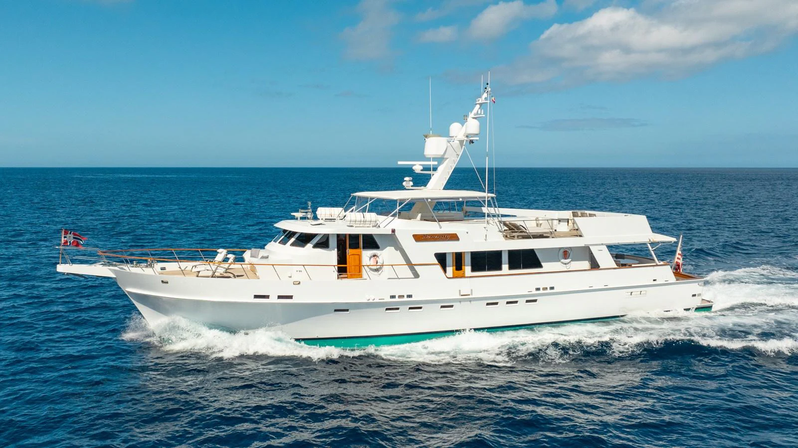 A sleek and elegant yacht cruises smoothly on the open sea under a clear blue sky. aboard SERENITY Yacht for Sale