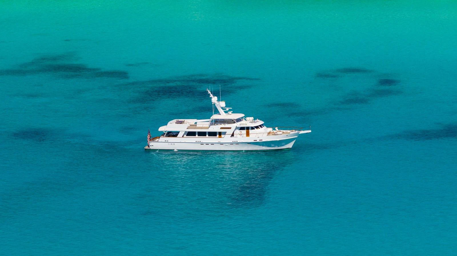 A luxurious yacht glides gracefully over clear turquoise waters, showcasing its elegant design. aboard SERENITY Yacht for Sale