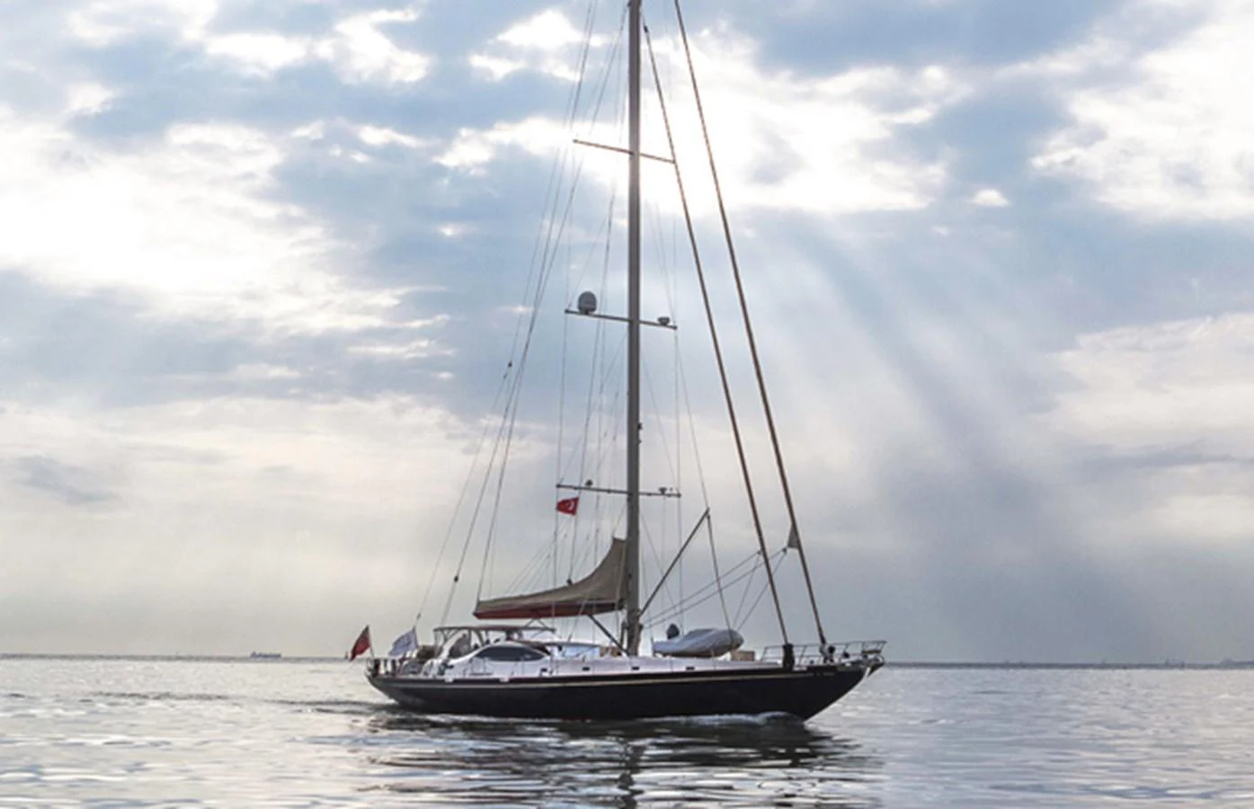 A sleek sailing yacht glides gracefully on calm waters under a dramatic sky. aboard GOLDEN TOUCH Yacht for Sale