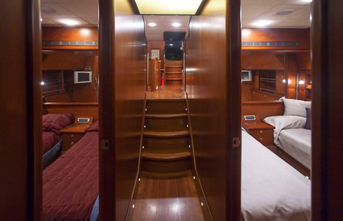 A warm and inviting cabin hallway with wooden finishes and cozy bedding. aboard GOLDEN TOUCH Yacht for Sale