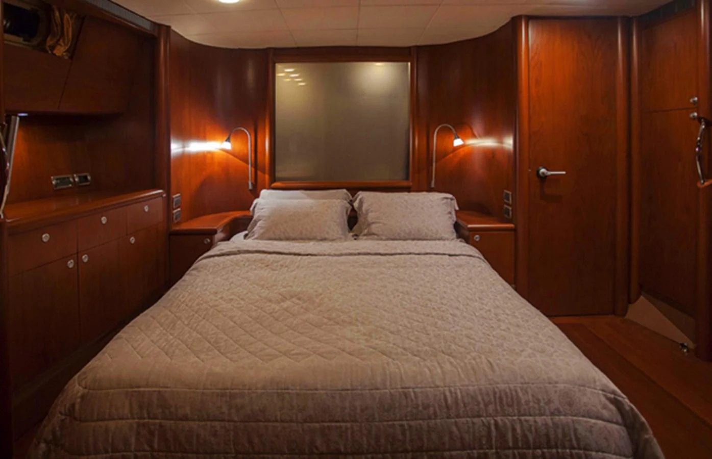 The stateroom features a cozy double bed with warm wooden finishes and ambient lighting. aboard GOLDEN TOUCH Yacht for Sale