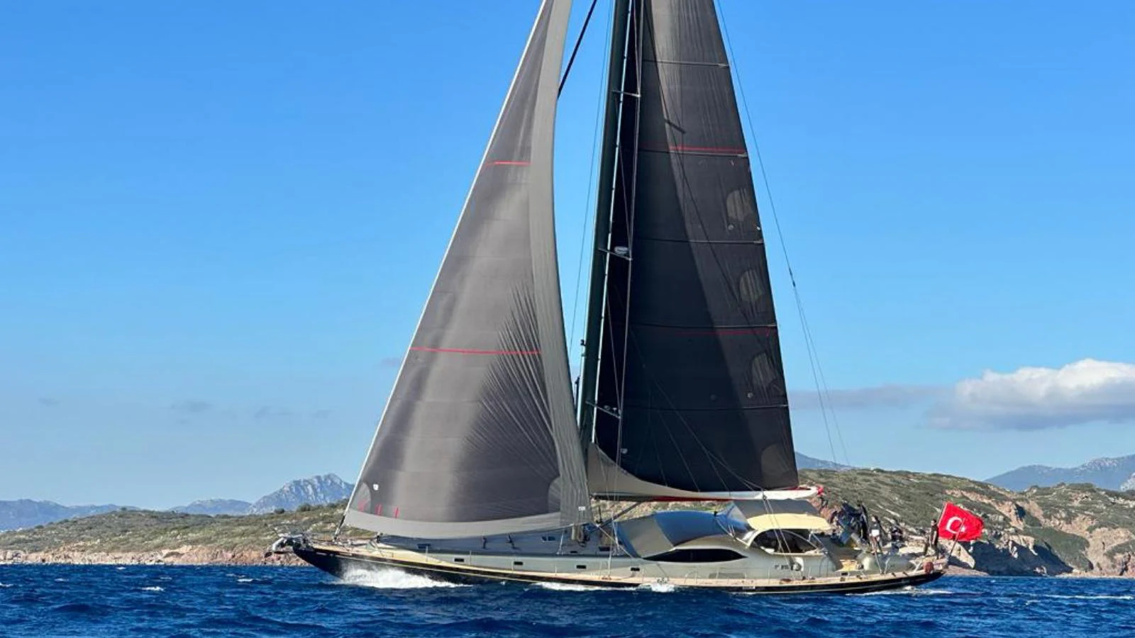 A sleek sailing yacht glides gracefully on the open sea, showcasing its impressive sails against a backdrop of scenic coastal landscape. aboard GOLDEN TOUCH Yacht for Sale