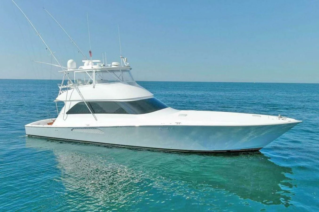 A sleek white yacht glides gracefully on calm blue waters under a clear sky. aboard VIKING 68 CONVERTIBLE Yacht for Sale