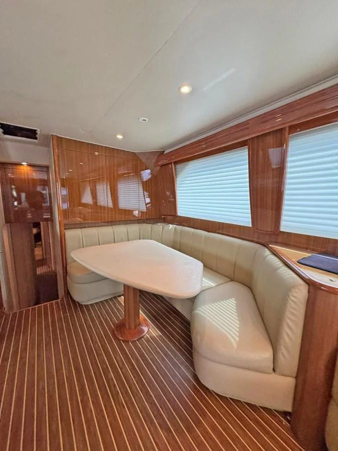 The yacht's interior features a cozy dining area with a wooden table and comfortable seating. aboard VIKING 68 CONVERTIBLE Yacht for Sale