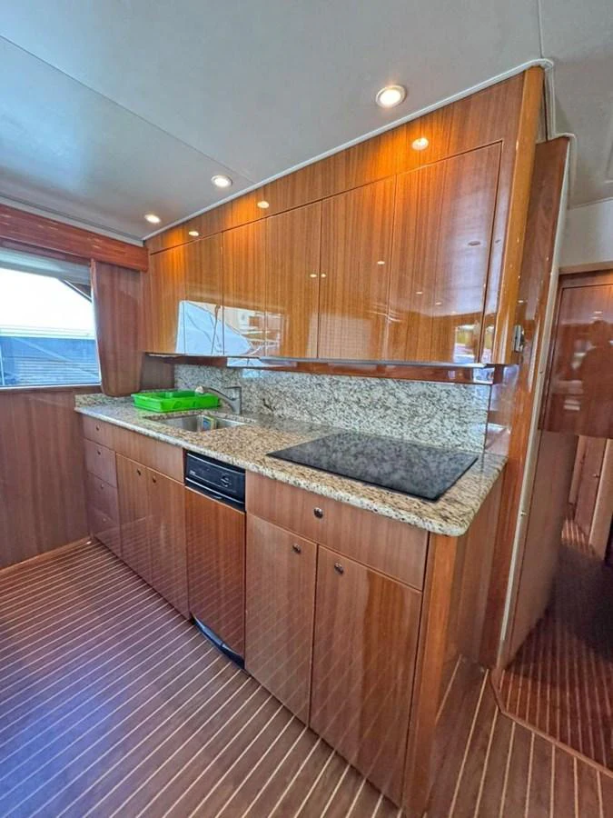 The yacht's galley features sleek wooden cabinetry, a granite countertop, and modern appliances. aboard VIKING 68 CONVERTIBLE Yacht for Sale