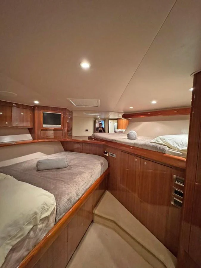 The guest stateroom features cozy twin beds with luxurious bedding and warm wood finishes. aboard VIKING 68 CONVERTIBLE Yacht for Sale
