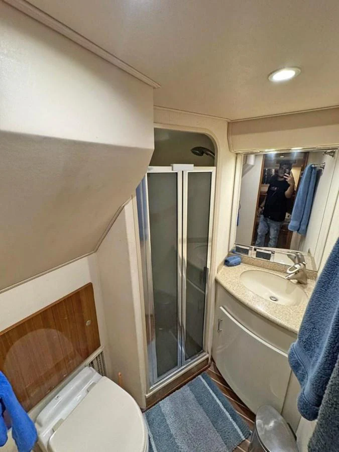The yacht's bathroom features a compact and functional design with a shower, sink, and toilet. aboard VIKING 68 CONVERTIBLE Yacht for Sale
