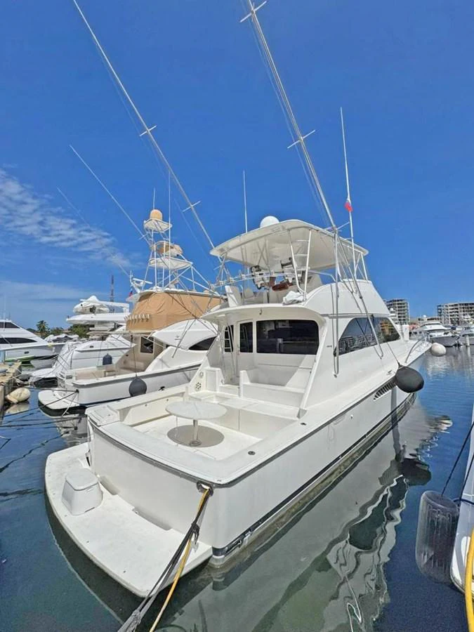 A sleek yacht docked at a marina, showcasing its spacious aft deck and towering antennas. aboard VIKING 68 CONVERTIBLE Yacht for Sale