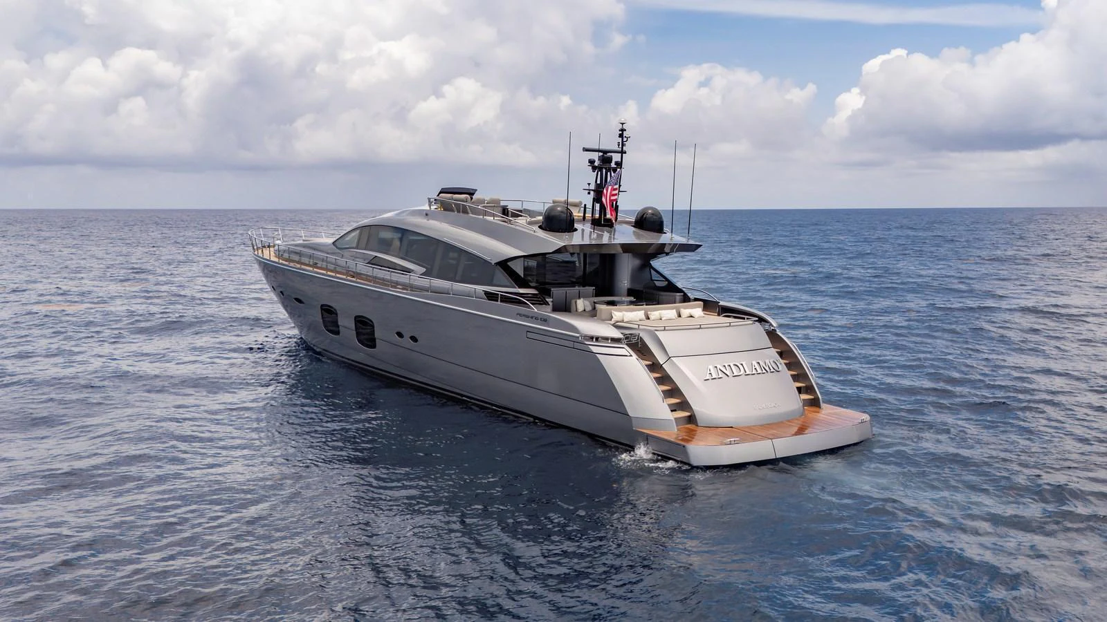 A sleek and modern yacht cruising on open waters under a partly cloudy sky. aboard ANDIAMO II Yacht for Sale