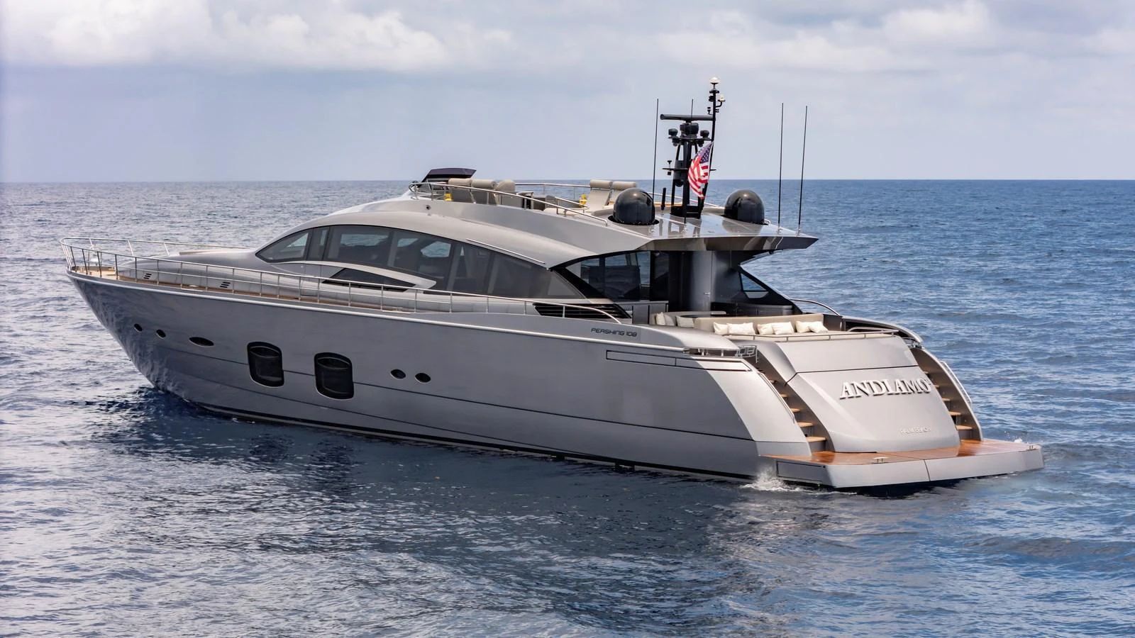 A sleek and modern yacht glides effortlessly on the open sea under a partly cloudy sky. aboard ANDIAMO II Yacht for Sale