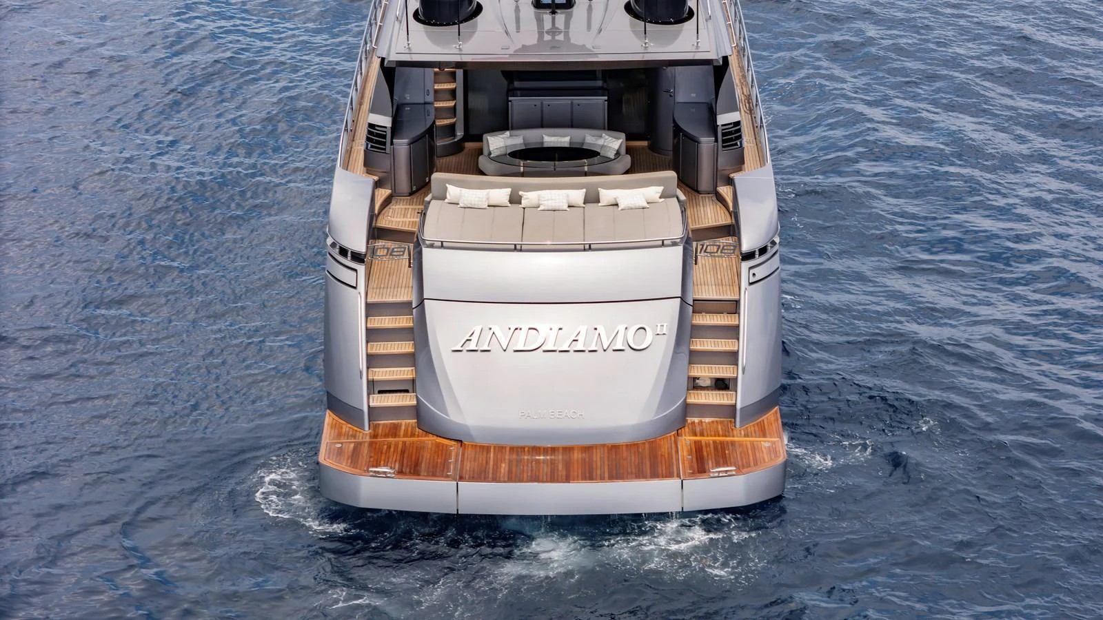 The yacht's aft deck features elegant wooden steps leading to a spacious lounging area. aboard ANDIAMO II Yacht for Sale