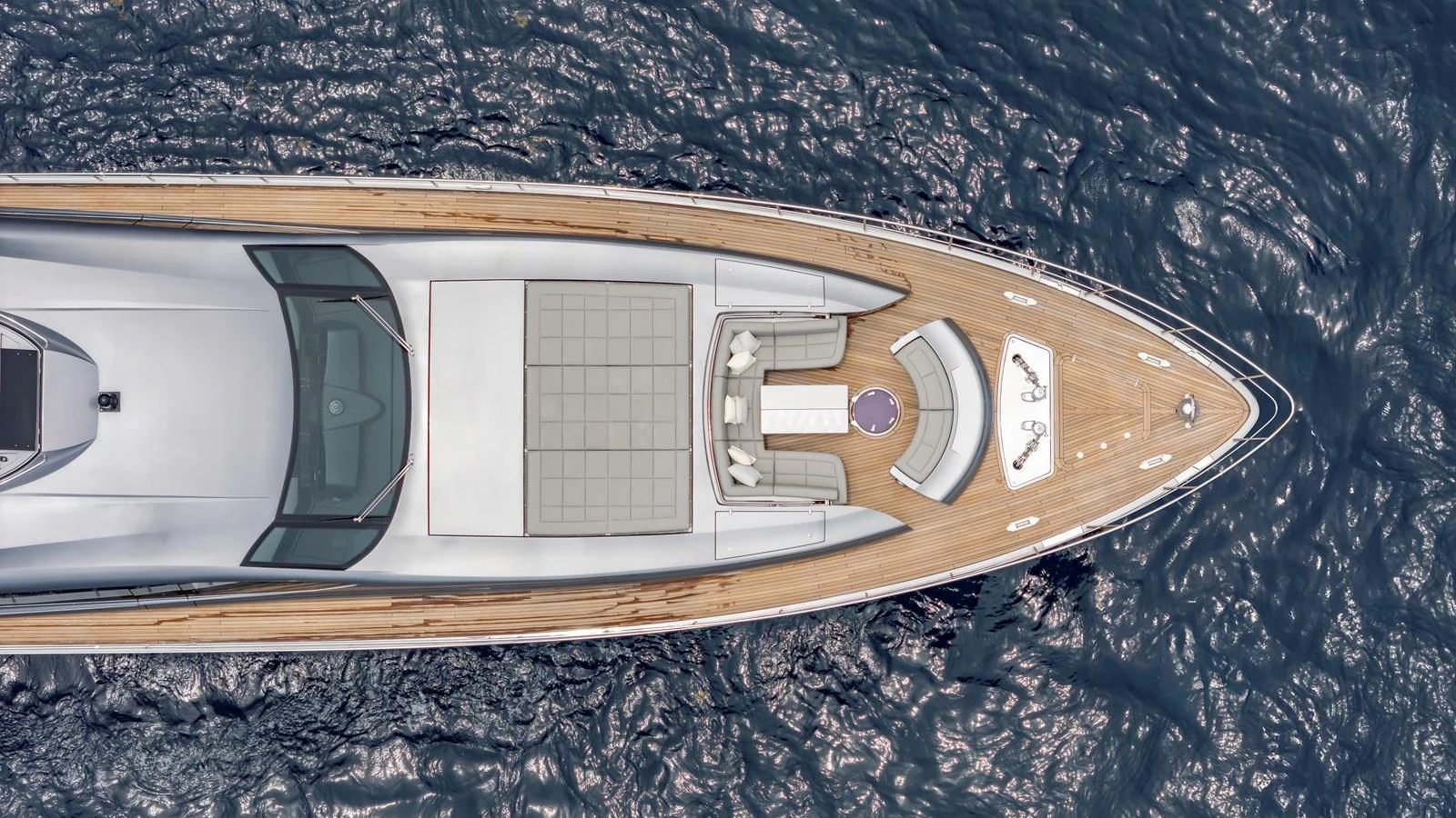 The foredeck of the yacht features a spacious sunbathing area with plush seating and a central table, surrounded by the serene ocean. aboard ANDIAMO II Yacht for Sale