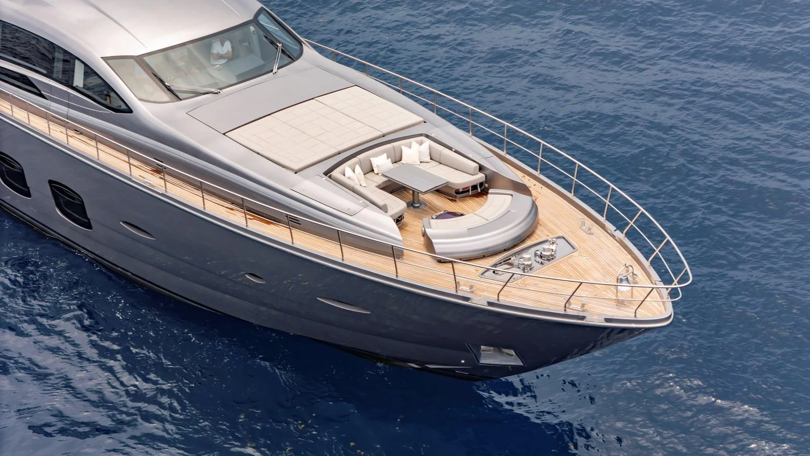 The sleek foredeck of the yacht features a spacious sunbathing area with luxurious seating and a table. aboard ANDIAMO II Yacht for Sale