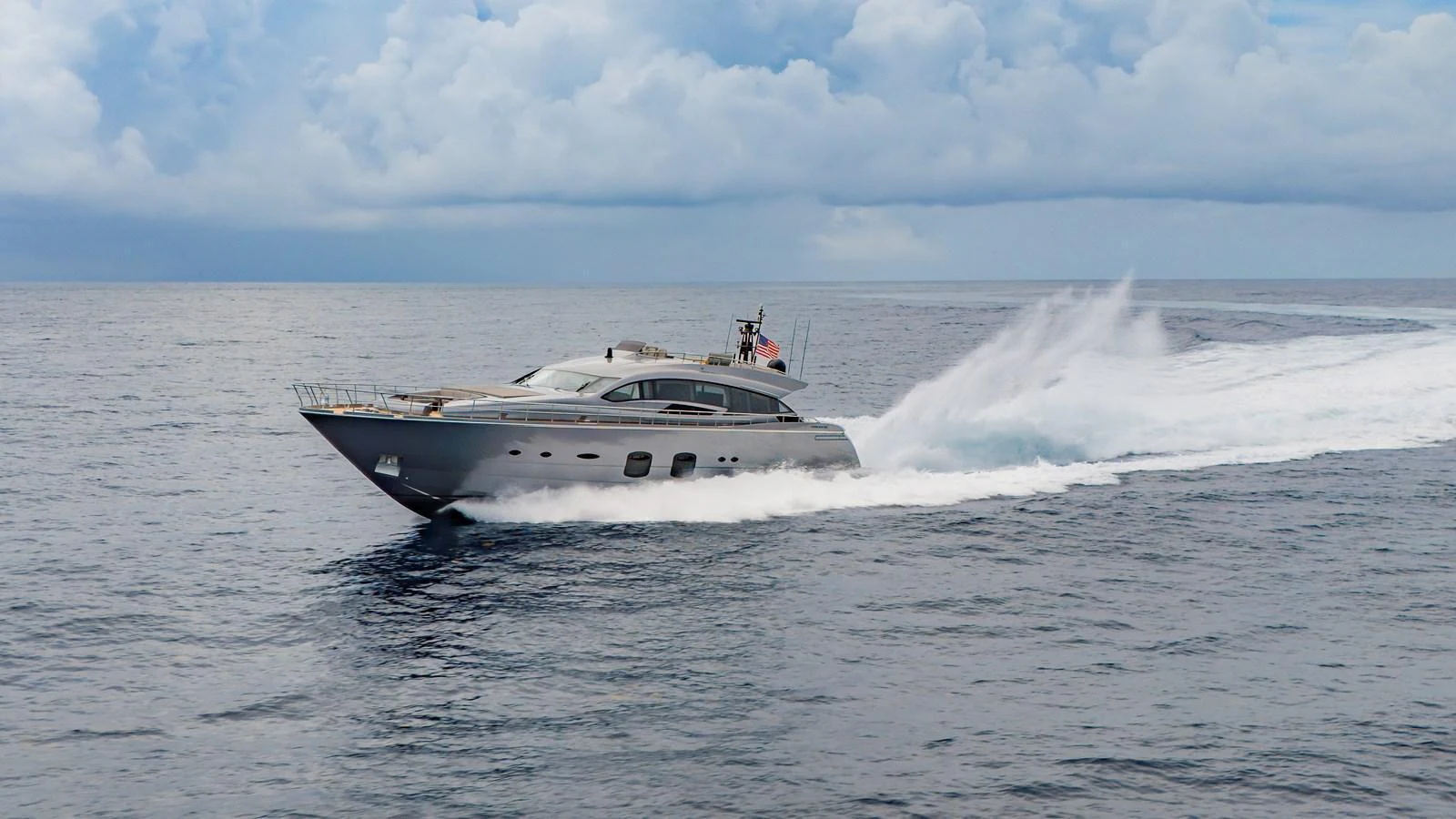 A sleek yacht cruises swiftly over calm waters under a partly cloudy sky. aboard ANDIAMO II Yacht for Sale