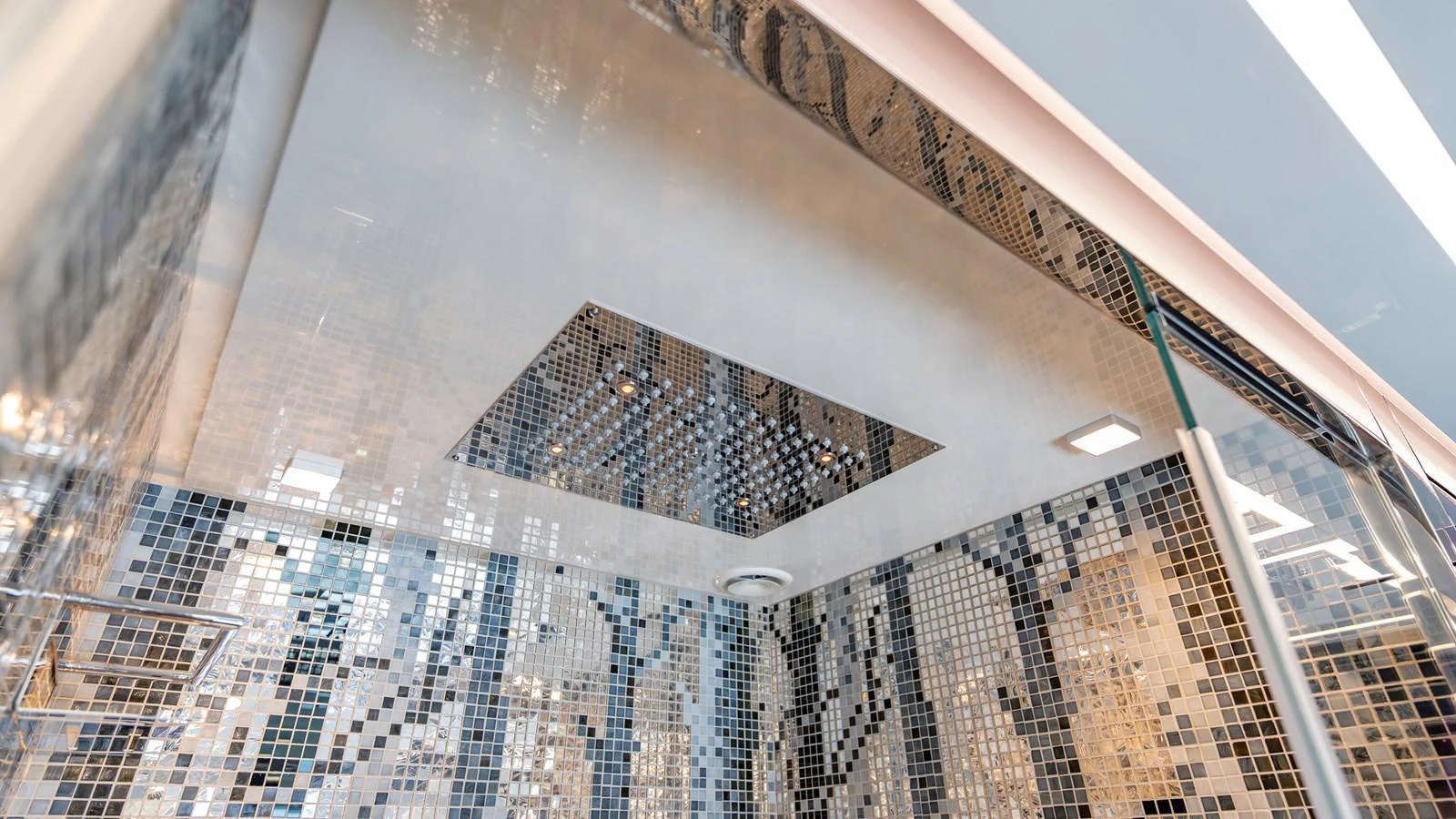 The yacht's bathroom features a modern mosaic tile design with a luxurious rain showerhead. aboard ANDIAMO II Yacht for Sale