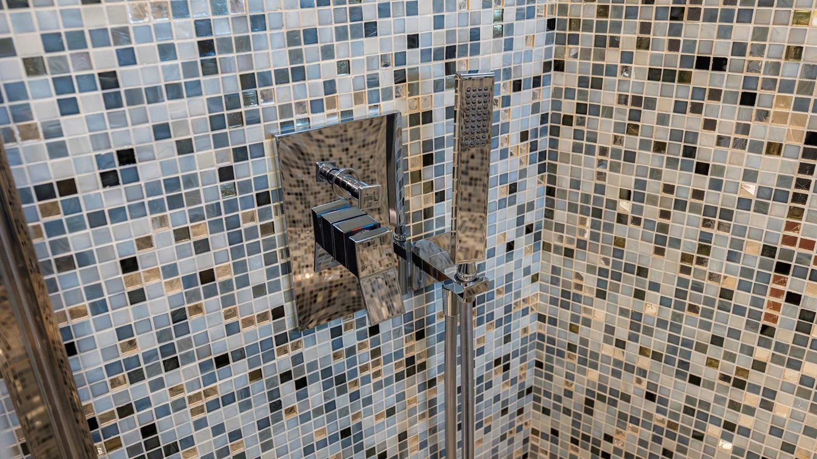 A close-up of a modern shower fixture set against a mosaic tile wall. aboard ANDIAMO II Yacht for Sale