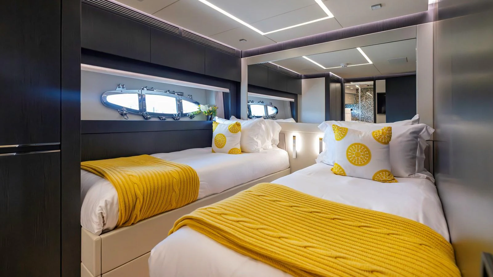 The twin stateroom features modern decor with cozy twin beds and vibrant yellow accents. aboard ANDIAMO II Yacht for Sale