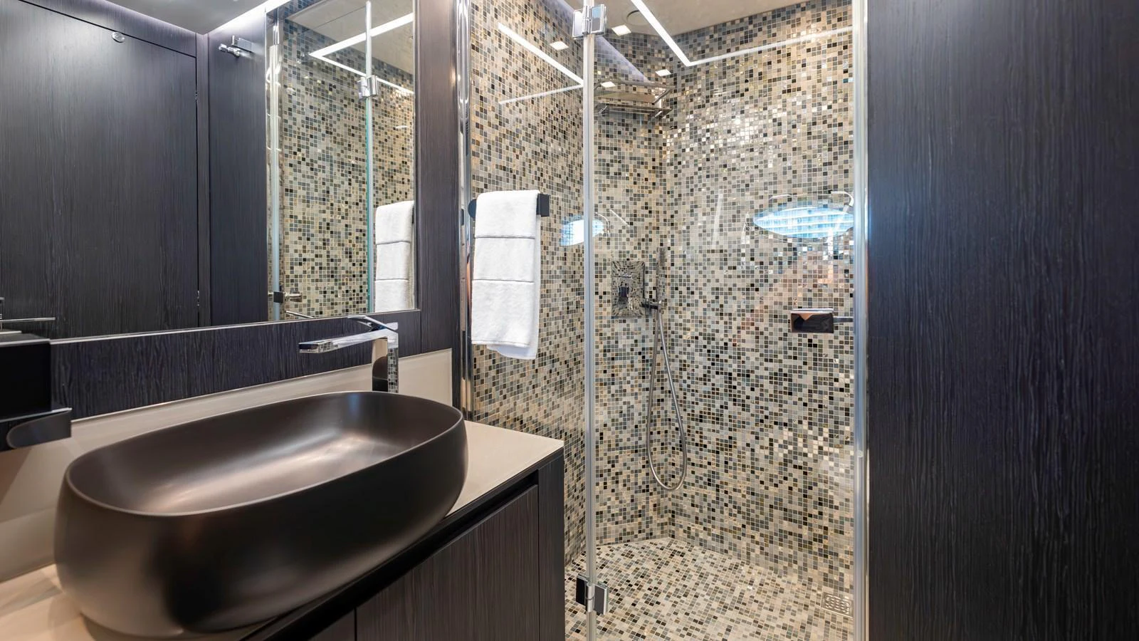 The yacht's bathroom features a modern design with a sleek black basin and a mosaic-tiled shower area. aboard ANDIAMO II Yacht for Sale