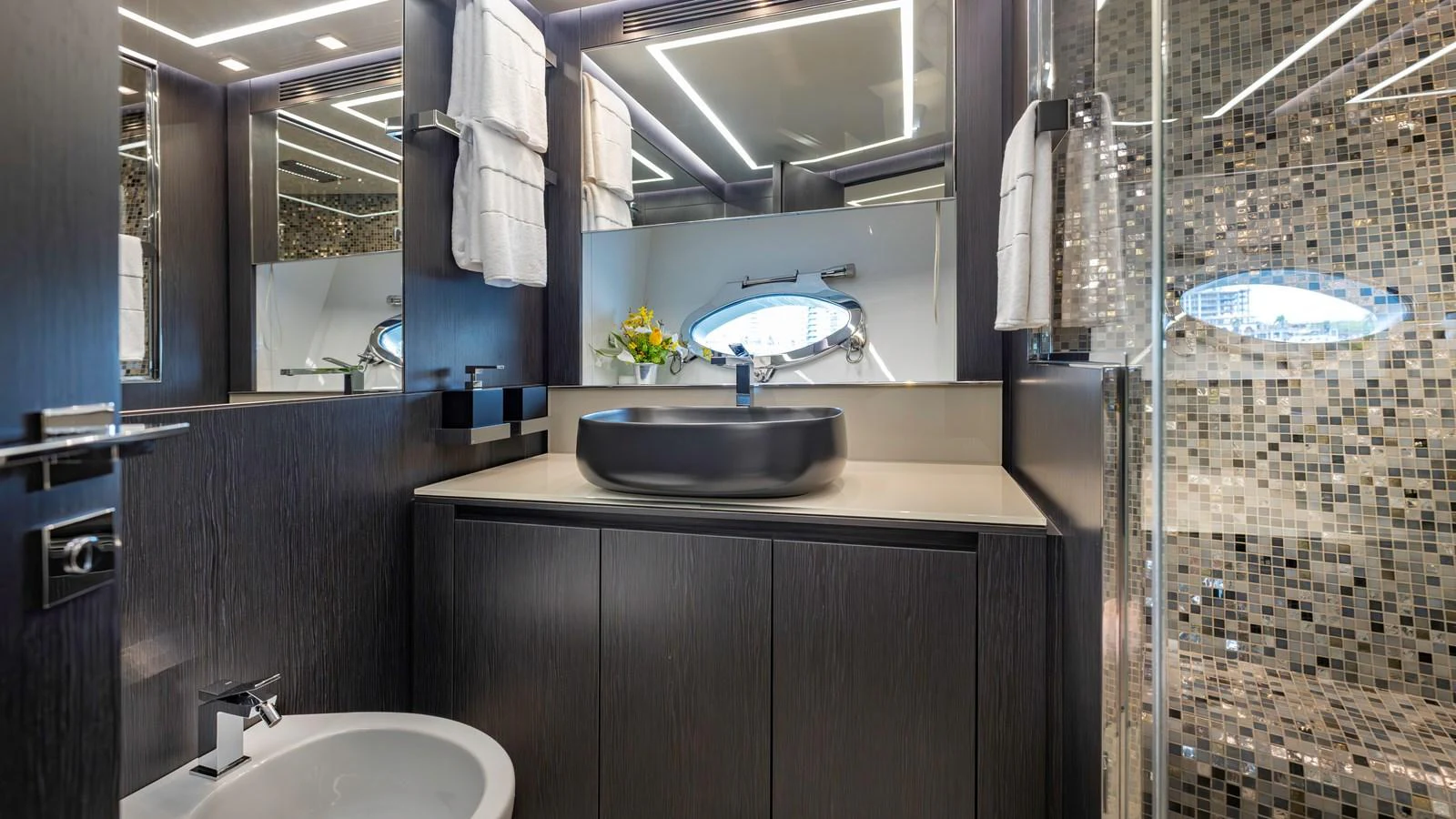 The yacht's bathroom features modern fixtures, a sleek black sink, and a stylish mosaic-tiled shower. aboard ANDIAMO II Yacht for Sale