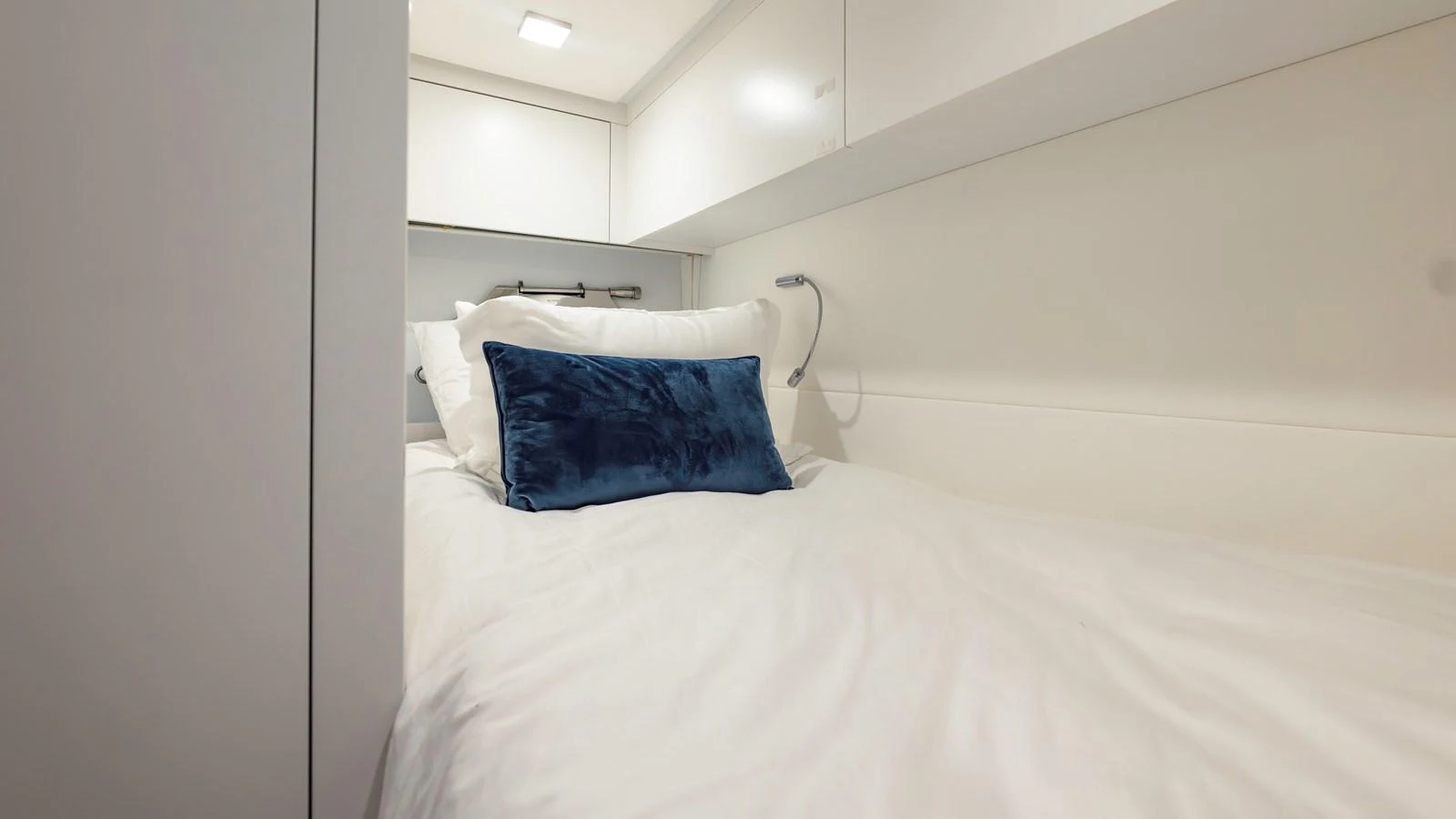 A cozy guest cabin with a plush bed and a blue accent pillow. aboard ANDIAMO II Yacht for Sale