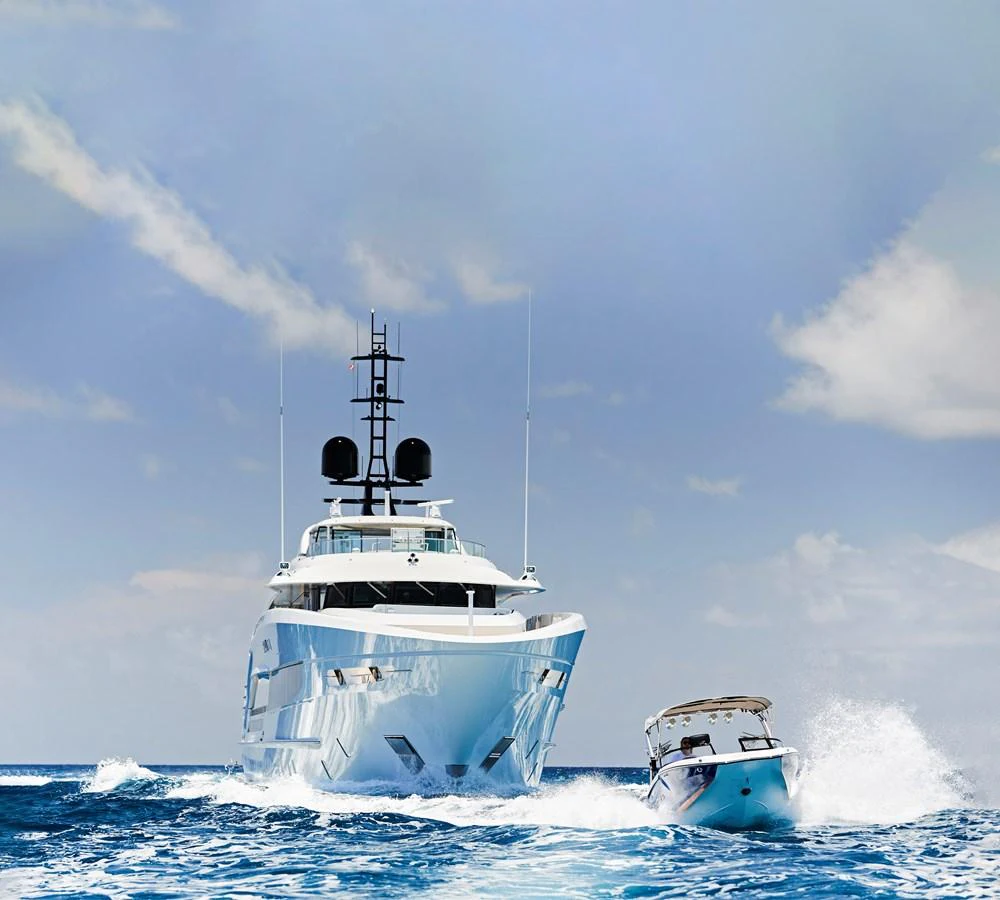 A stunning yacht cruises through the open sea with a tender boat alongside. aboard ARKADIA Yacht for Sale